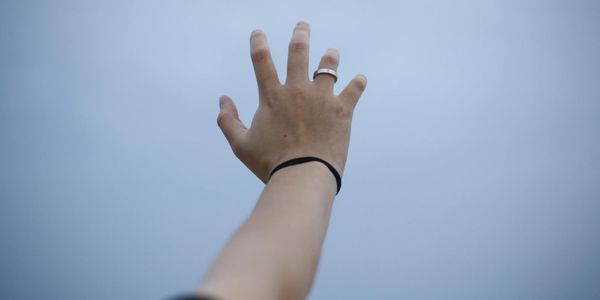 Close up of hands reaching for the sky